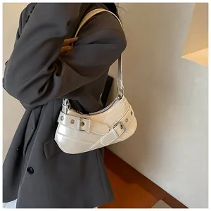 Detail of white glossy underarm bag featuring decorative buckles and metal eyelets
