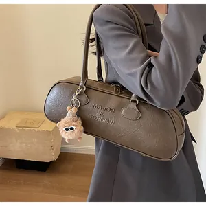Detail of dark brown vintage faux leather baguette bag with plush charm and embossed logo
