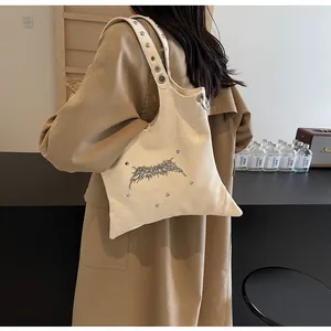 Dettaglio borsa a tracolla Y2K crema in finta pelle con anello in metallo e logo spine