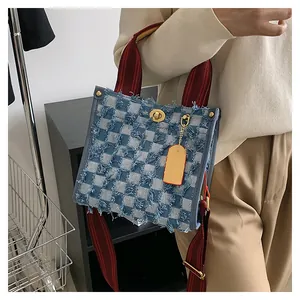 Detail of vintage denim plaid tote bag featuring red woven handles and gold turn-lock