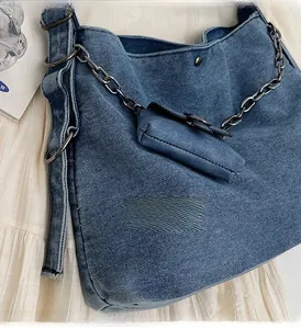 Detail of blue denim shoulder bag texture with black metal chain and mini pouch