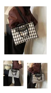 Detail of tweed tote bag showing black leather straps and golden metallic hardware