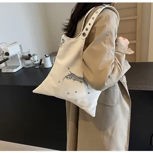 Dettaglio borsa a tracolla in pelle crema con spine metalliche e occhielli d'argento