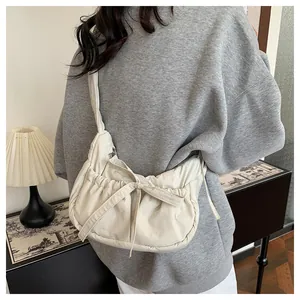 Detail of creamy white drawstring nylon bag with decorative bow and pleated texture