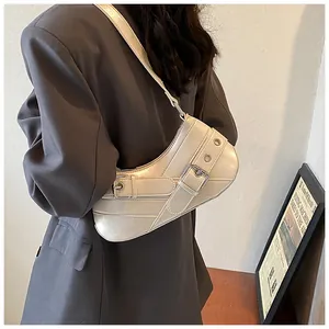 Detail view of stylish ivory leather underarm bag with decorative metal eyelet buckles