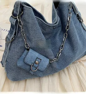 Detail of blue denim tote bag featuring silver chain strap and mini square bag charm