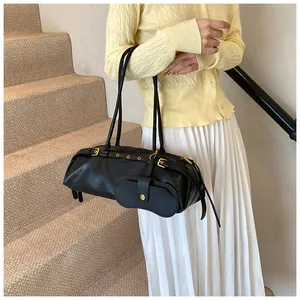 Detail of black leather motorcycle style bag with gold buckles and mini pouch attachment