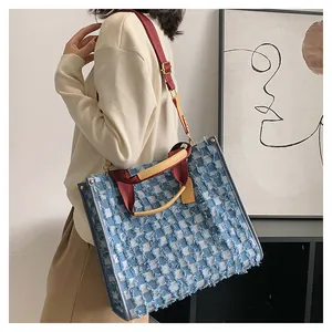 Detail view showing blue and white checkered denim tote bag with tassel fringe edges