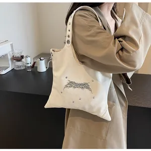 Dettaglio borsa a tracolla bianco crema con logo spina argento e occhielli metallici