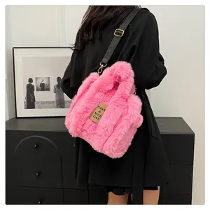 Detail of pink plush tote bag with embroidered label and adjustable black shoulder strap