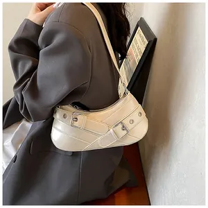 Detail of creamy white underarm bag with silver buckles and metallic eyelets on the strap