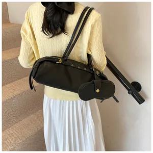 Detail of black faux leather shoulder bag with metallic buckle and eyelet decoration
