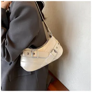 Detail view of cream hobo bag with buckled belt straps and metal eyelets on model