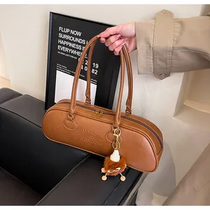 Close-up of brown vintage Boston bag featuring a logo engraving and a cute plush charm