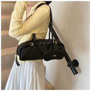 Detail of black leather baguette bag with metal buckle and detachable mini pouch
