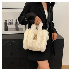 Detail of cream plush tote bag with brown leather tag and detachable nylon strap