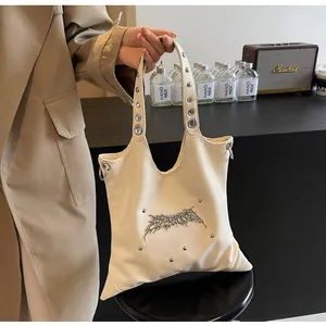 Dettaglio della borsa a tracolla color crema a forma di stella con borchie punk e decorazioni