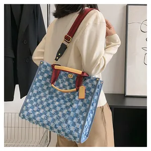 Detail of blue and white checkered tweed tote bag with red strap and metal handle