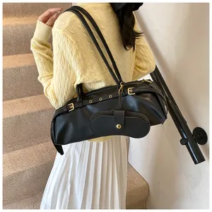 Detail of black leather shoulder bag featuring metal eyelets and decorative side buckles