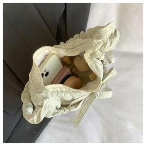 Detailed interior of a beige pleated nylon crossbody bag showing large storage capacity
