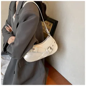 Detail of white hobo bag featuring glossy leather with silver buckles and diagonal stitching