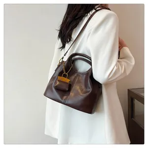Close-up of vintage dark brown faux leather handbag showing dual handles and golden chain detail