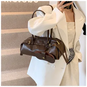 Detail of dark brown leather shoulder bag with metallic buckles and mini pouch accessory