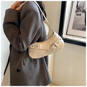 Detailed view of cream leather underarm bag with metal eyelets on model in grey blazer