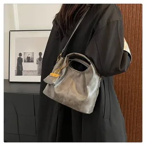 Detail of dark gray vintage satchel featuring gold chain link and mini pouch accessory