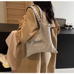 Dettaglio borsa a tracolla argento metallizzato con ornamento gotico e borchie