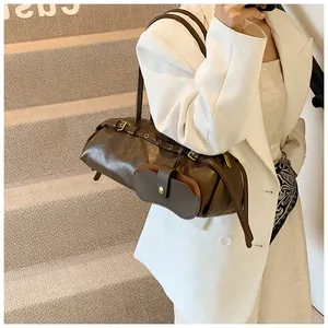 Detailed view of deep brown leather shoulder bag with vintage buckle and utility pouch