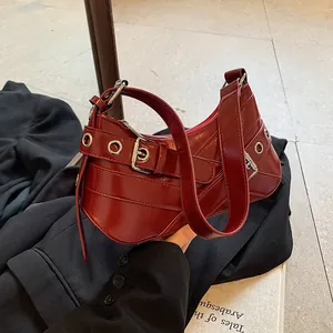 Retro deep red underarm bag with glossy finish and buckle details on a dark sleeve