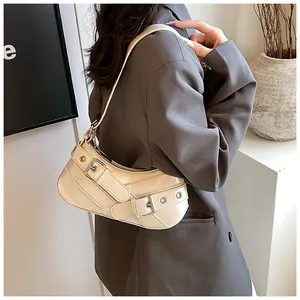 Detail of beige shoulder bag with silver metal buckles and punk-style grommet straps