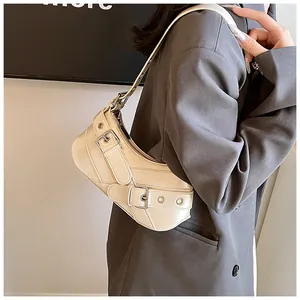 Close-up of creamy white crescent shoulder bag featuring silver buckle belt detailing