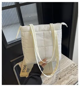 Detailed view of white quilted puffer tote bag on marble surface with a book