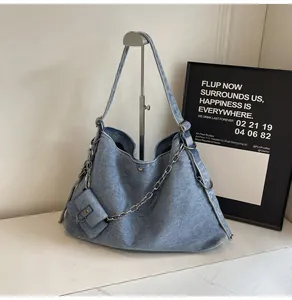 Close-up of blue denim hobo bag with silver chain detail and small hanging pouch