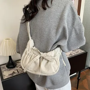 Chic cream nylon crossbody bag with bow drawstring and pleated texture on model