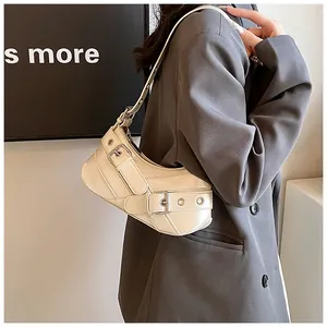 Detail of cream white crescent underarm bag with buckle straps and metal eyelets
