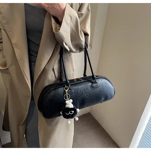 Close-up of black lychee texture leather Boston bag with brand logo and plush pendant