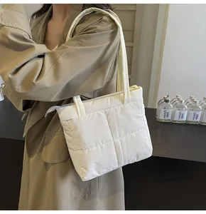 Close-up of white quilted puffer shoulder bag with elegant stitch patterns and soft nylon texture