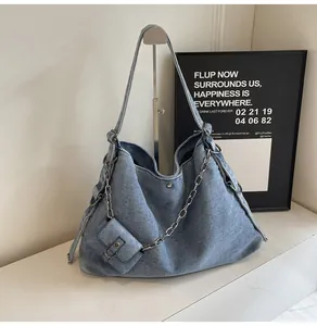 Close-up of blue denim tote bag featuring chunky metal chain and small hanging pouch