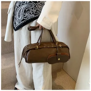 Detail of dark brown leather Boston bag with a unique glasses-case charm and gold buckles