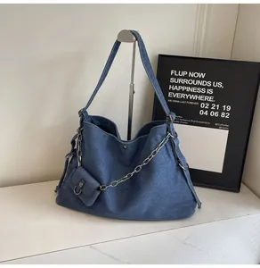 Detail of blue denim tote bag with silver chain and matching mini pouch accessory