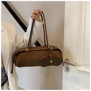 Detail view of a vintage dark brown cylindrical baguette bag with metal buckle straps