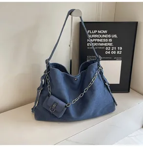Detail of blue denim tote bag with silver chain strap and mini flap pouch charm