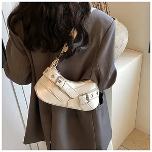 Detail of cream underarm bag with silver buckles and metal eyelets on PU leather