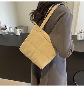 Detailed view of beige quilted shoulder bag with diamond stitching on grey blazer