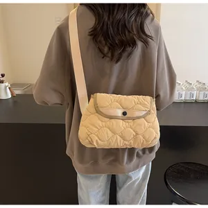 Detail of beige quilted puffer crossbody bag with wave texture and wide canvas strap