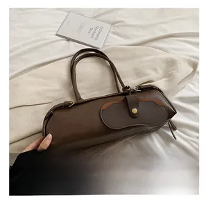 Detail showing the buckle pocket and matte leather texture of the dark brown baguette bag