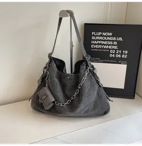 Detail of grey denim tote bag featuring wavy pleats and decorative silver metal chain link